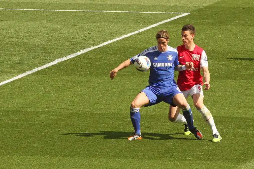 Fernando Torres i ett blått Chelsea-ställ kontrollerar en fotboll med Laurent Koscielny bakom sig.