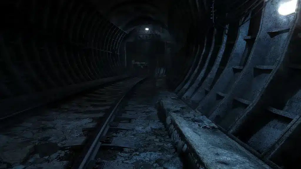En mörk, stämningsfull vy av en övergiven tunnelbanetunnel med rostiga metallstöd och svag belysning.